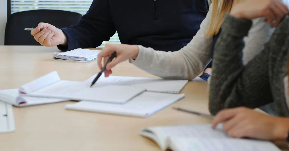 Two colleagues working through documents together at a table