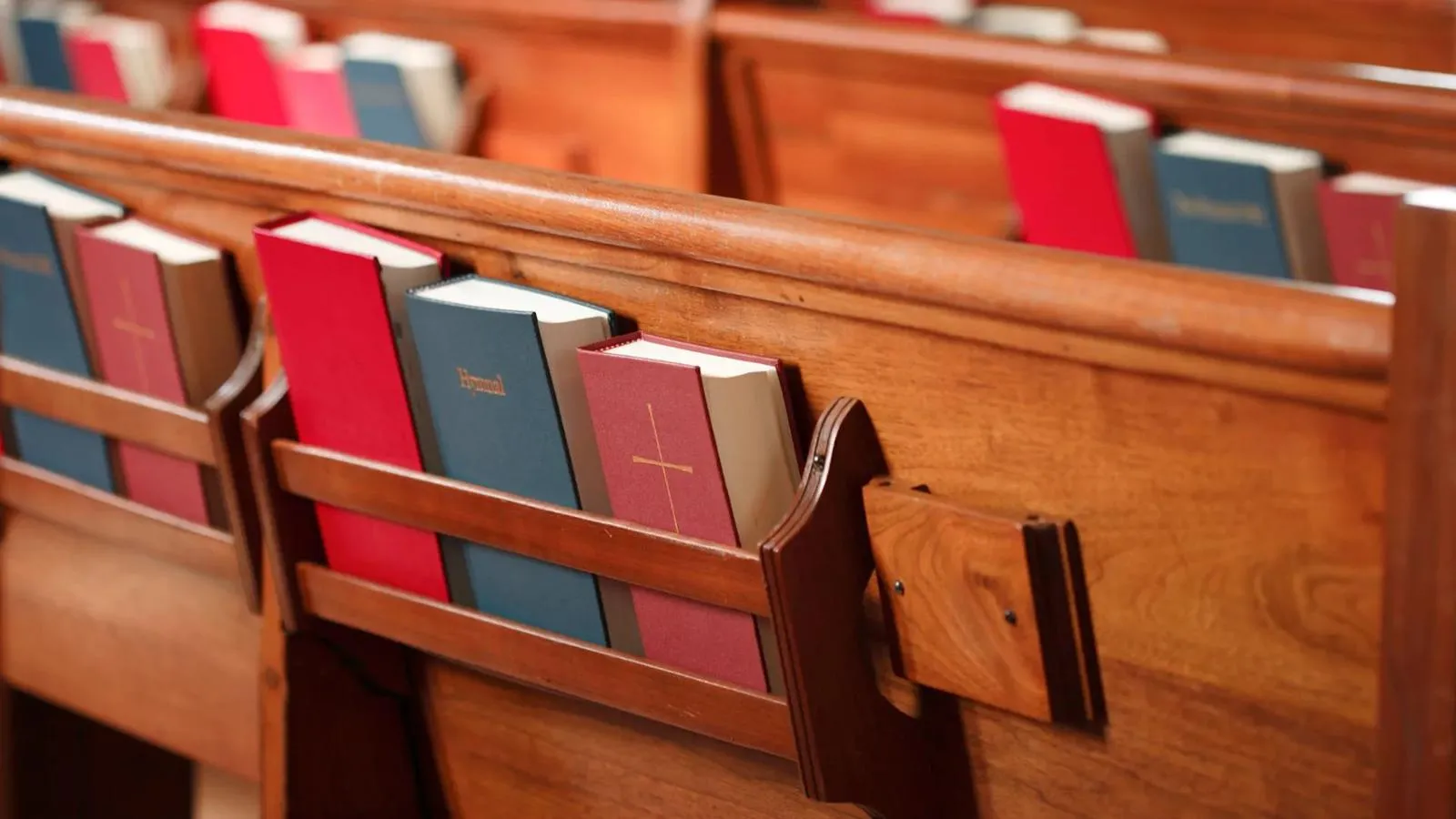 Wooden pews with hymnals and Bibles in the racks