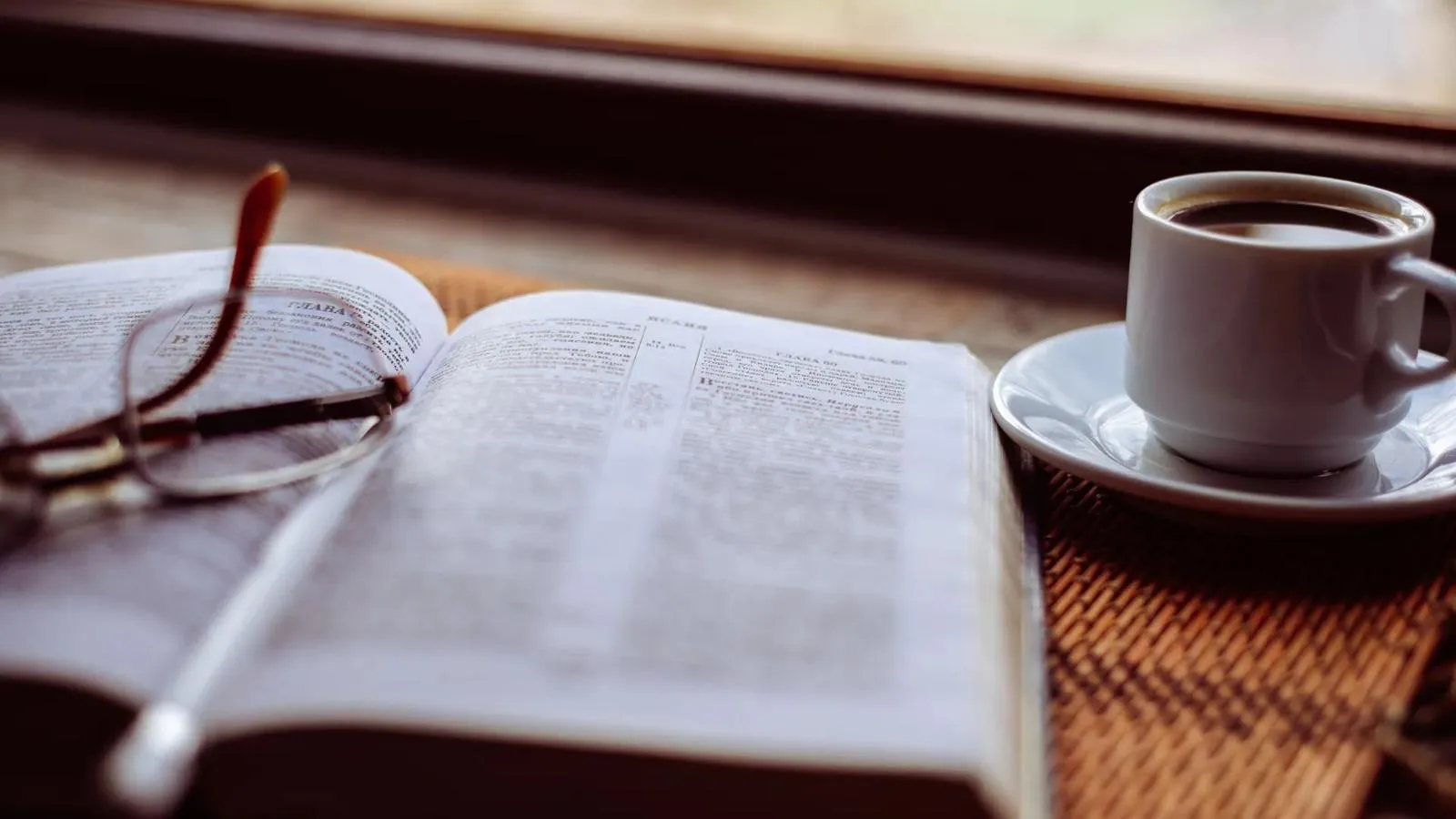 Open Bible with reading glasses and a cup of coffee