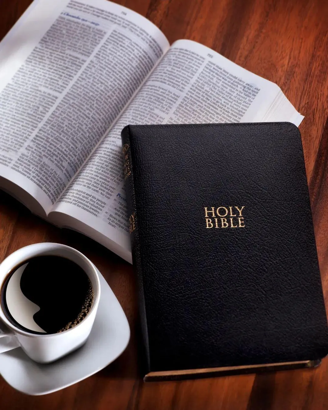 Black Bible and a cup of coffee on a wooden table