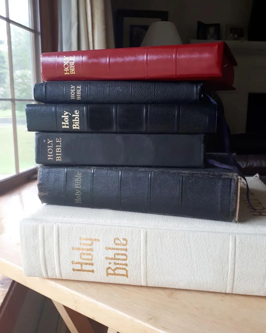 Stack of Bibles on a table by a window