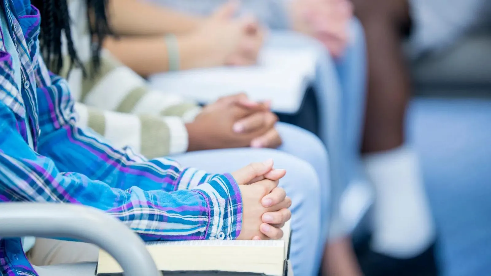Clasped hands of people seated in a row